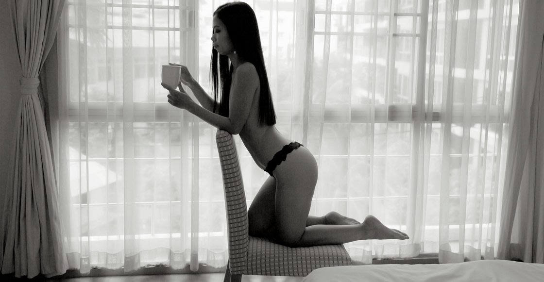 An asian masseuse kneeling seductively on a chair